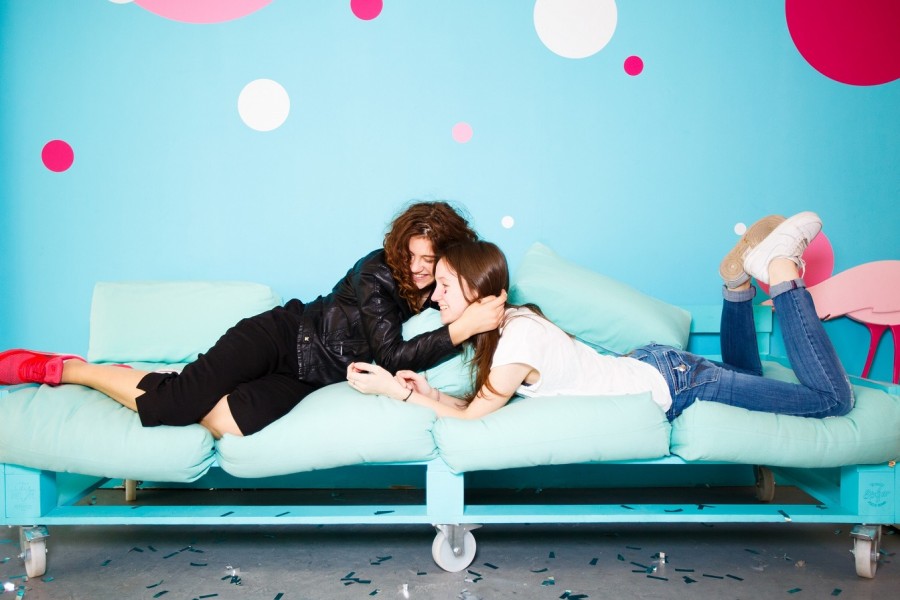 Zwei Freundinnen auf einem Sofa umarmen sich und lachen, auf dem Boden liegt Konfetti. Lebenslagen, Feiern, Umzug, Verlobung, Hochzeit, Abiabschluss, - Pixabay